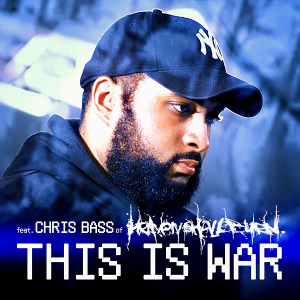 Cover image for the song 'This Is War' featuring a close-up of a bearded man wearing a black cap and hoodie, with a serious expression. The background has a blue-toned, blurred effect. The song title 'This Is War' is displayed in bold, glitch-style white text, with 'feat. Chris Bass of Heaven Shall Burn' written above it.